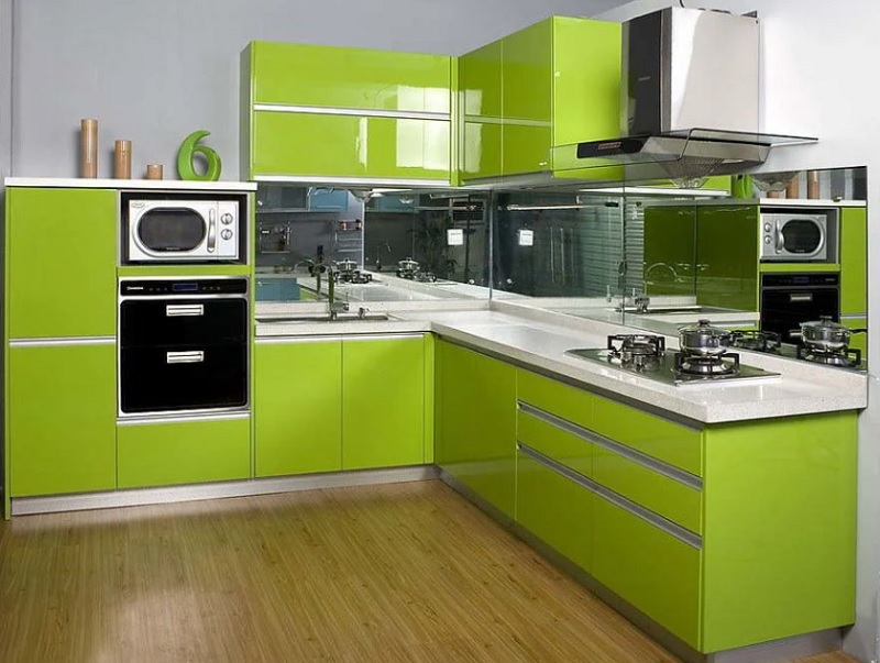 Зеленая современная угловая глянцевая кухня с каменной столешницей в стиле минимализм без ручек