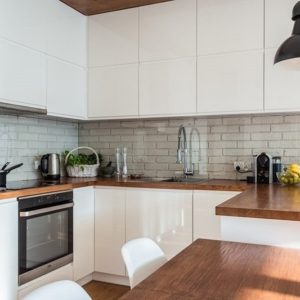 Белая высокая кухня с деревянной столешницей с фасадами без ручек