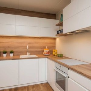 Белая угловая кухня без ручек с деревянной столешницей горизонтальными верхними шкафами