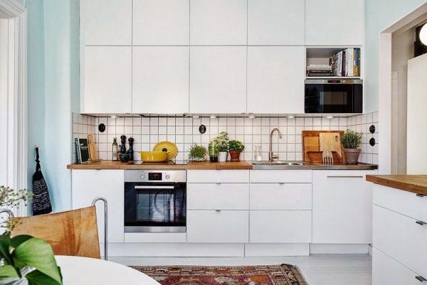 Белая красивая высокая кухня с деревянной столешницей в скандинавском стиле
